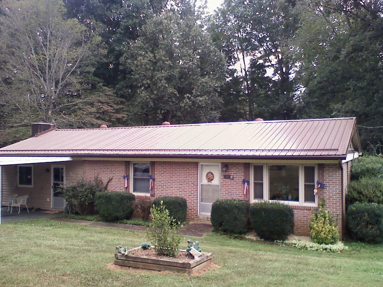 Bronze metal roof on a brick ranch home with a carport in Sedalia