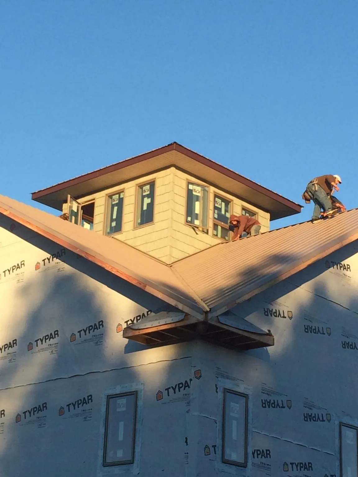 Roofers working around a rooftop cupola on a new metal roof at sunset — Roof Waterproofing in Sedalia by Roofing Brothers